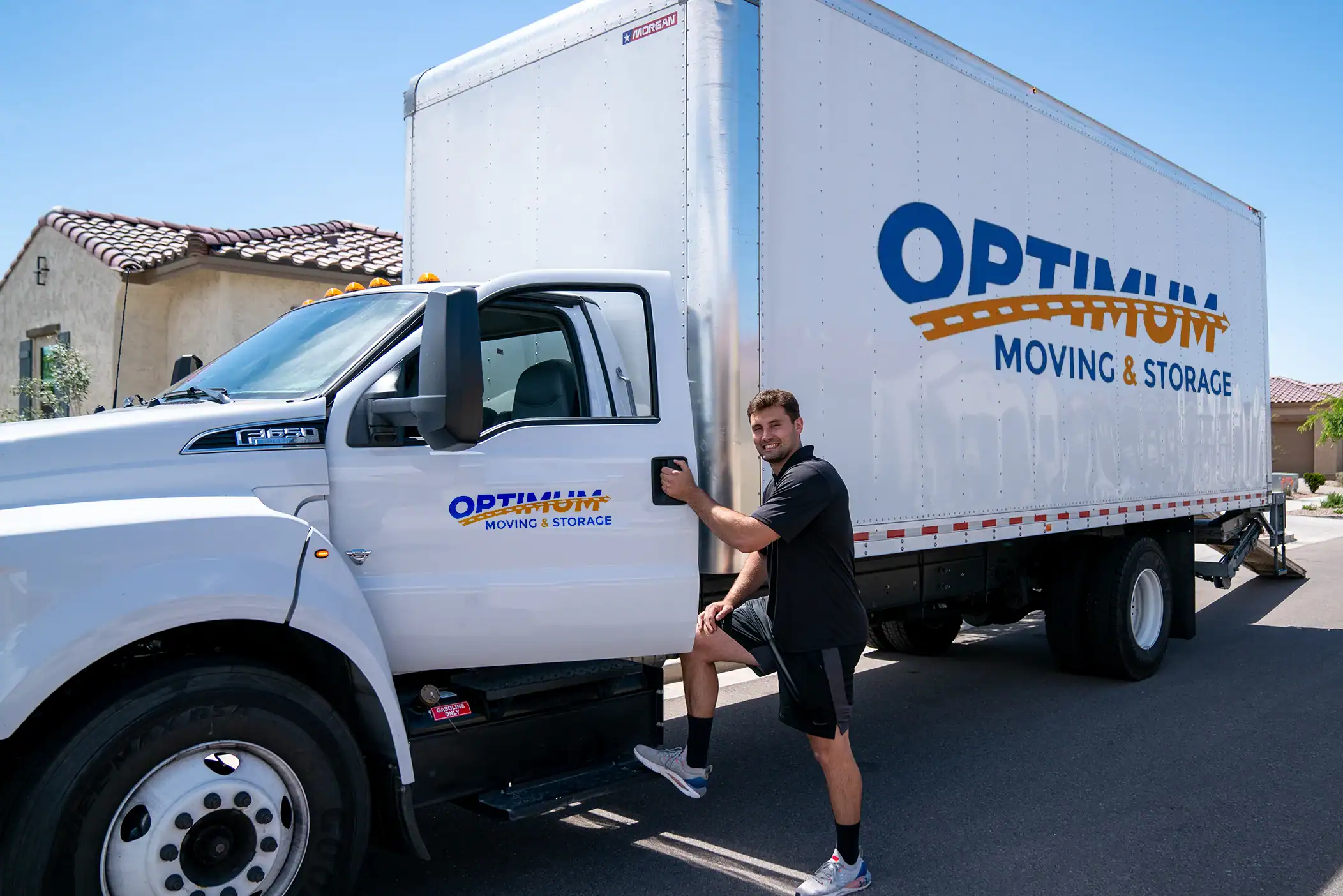 Moving truck with Optimum Moving & Storage branding in a residential area.