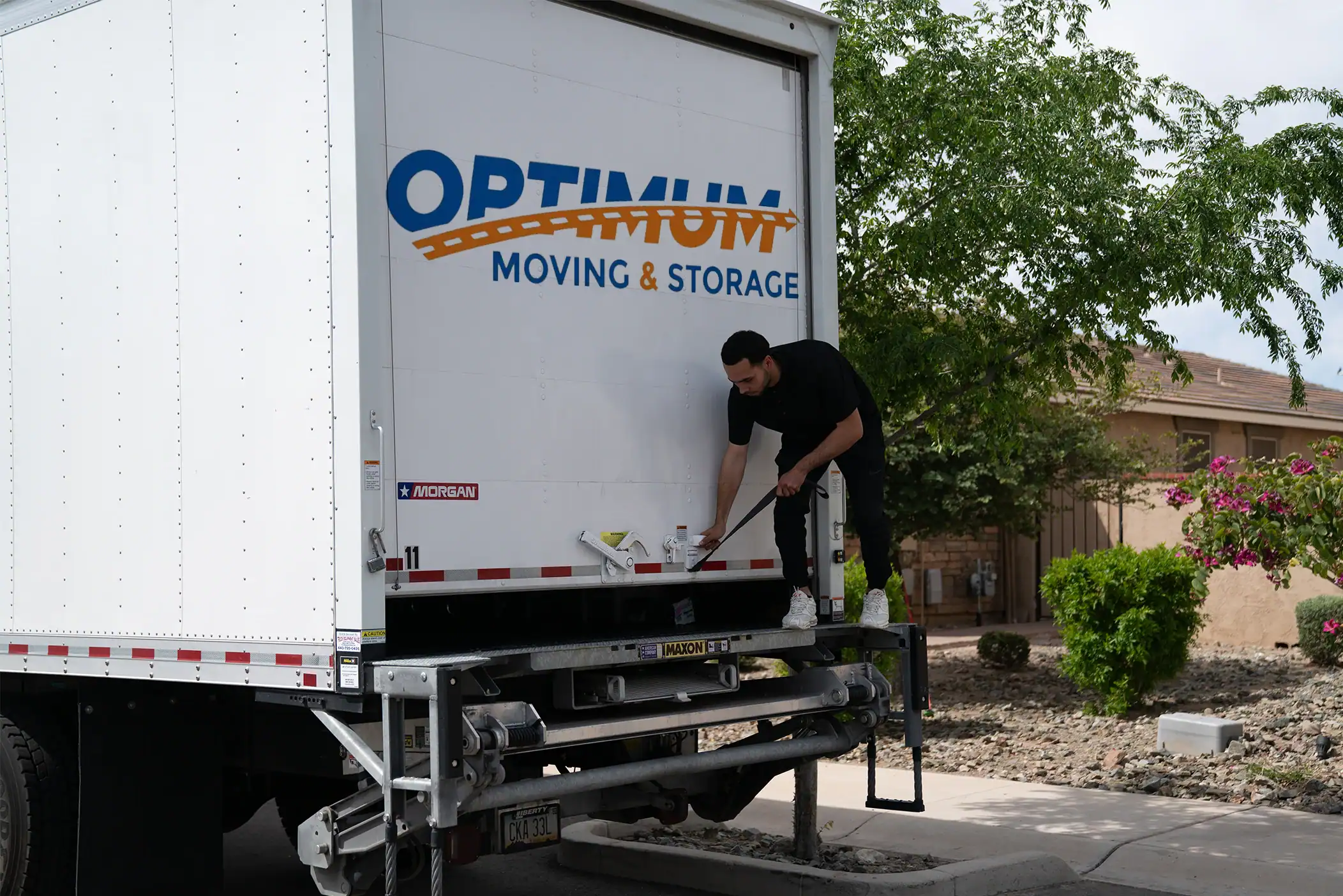 Professional mover loading a truck with Optimum Moving & Storage branding.